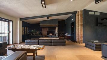 Una sala de estar moderna con chimenea, asientos de cuero y una mesa de centro con revistas.