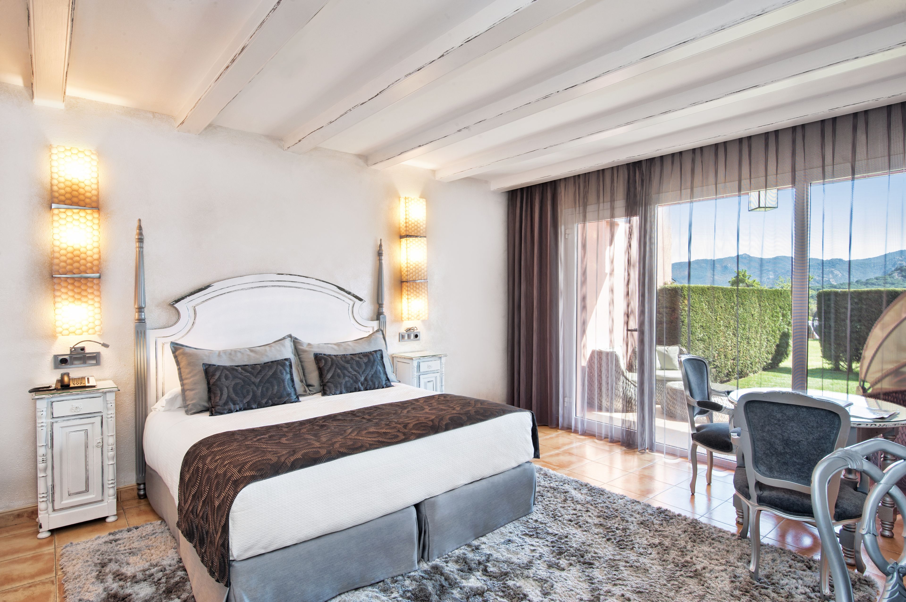 Een slaapkamer met een bed, nachtkastjes, een stoel en uitzicht op de omgeving.