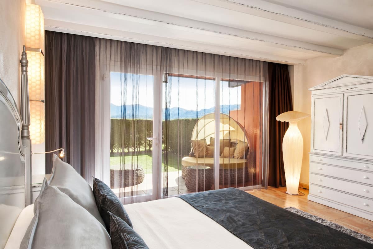 Ein Schlafzimmer mit einem großen Bett, einem Schminktisch und Blick ins Freie.
