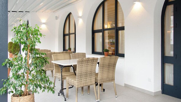 A covered outdoor seating area with wicker furniture and potted plants. - Hotel Medes II (Torroella de Montgrí)