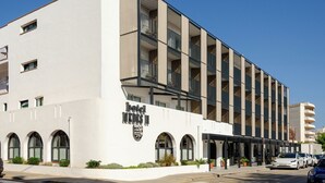 A modern hotel with a white facade, multiple balconies, and a covered entrance area. - Hotel Medes II (Torroella de Montgrí)