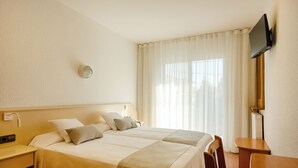 A hotel room with a bed, bedside tables, a desk, a chair, a flat-screen TV mounted on the wall, and a large window with curtains. - Hotel Medes II (Torroella de Montgrí)