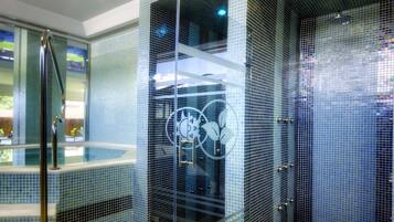 Un baño moderno con un jacuzzi de vidrio, paredes con azulejos y vistas al exterior.