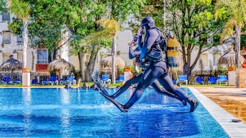 Guests can enjoy swimming and diving in the resort's pool surrounded by lush tropical plants and trees.