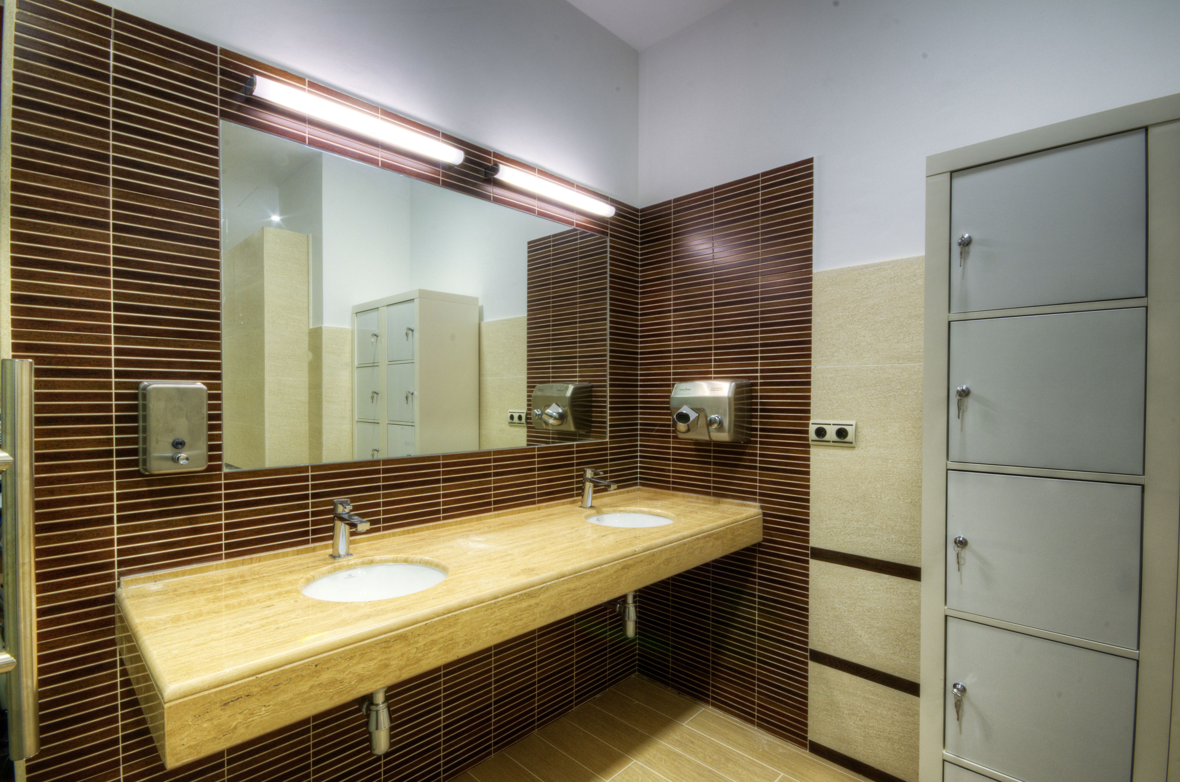 Baño público con dos lavabos, un espejo y un armario.