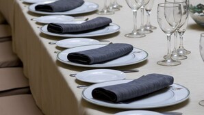 A long dining table set with plates, folded napkins, and wine glasses. - Louty Simba (Chilches)