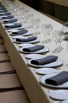 Una larga mesa de comedor con platos, servilletas dobladas y copas de vino.