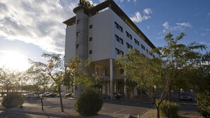 A multi-story hotel with a prominent entrance, a parking lot, and surrounding greenery. - Louty Simba (Chilches)