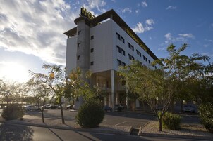 Un hotel de varios pisos con una entrada destacada, un estacionamiento y zonas verdes circundantes.