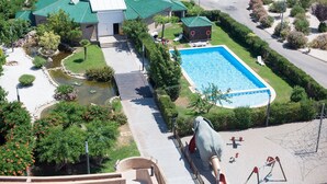 A swimming pool surrounded by a landscaped garden, a small pond, and a large elephant statue. - Louty Simba (Chilches)