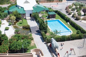 Una piscina rodeada de un jardín ajardinado, un pequeño estanque y una gran estatua de elefante.