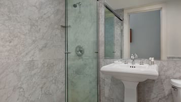 A bathroom with a glass-enclosed shower, a white pedestal sink, and a toilet.