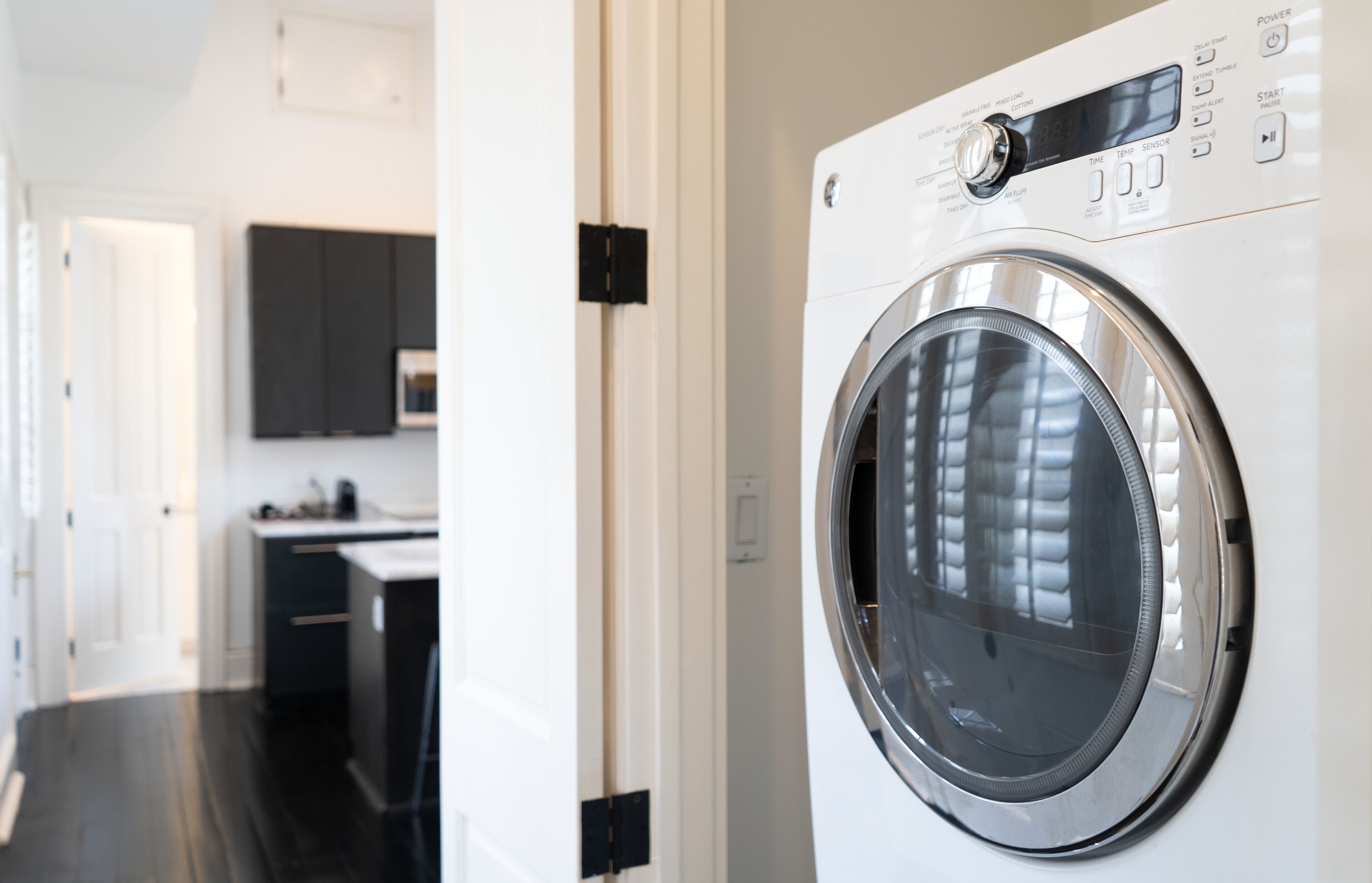 A modern laundry room with a front-loading washing machine, a microwave, and a sink.