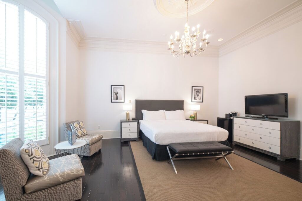 Ein modernes Schlafzimmer mit einem großen Bett, Nachttischen, einem Fernseher und einer Pendelleuchte.