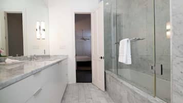 Un bany modern amb dutxa envidriada, taulell de marbre i un armari amb vestidors.