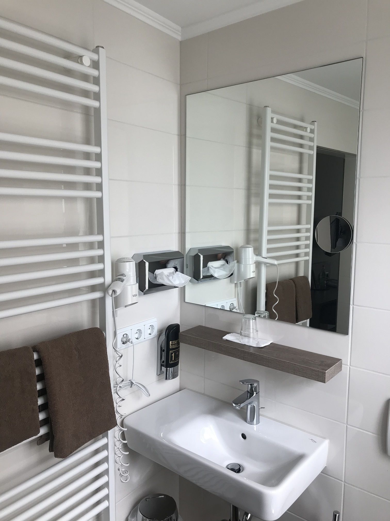 A modern bathroom with a white sink, towel rack, and a mirror.