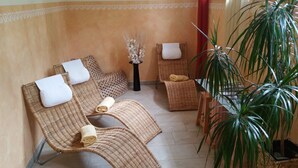 A seating area with wicker chairs, a small table with a vase, and a large potted plant. - Mayerhofer - Hotel - Restaurant - Partyservice - Tagung (Aldersbach)