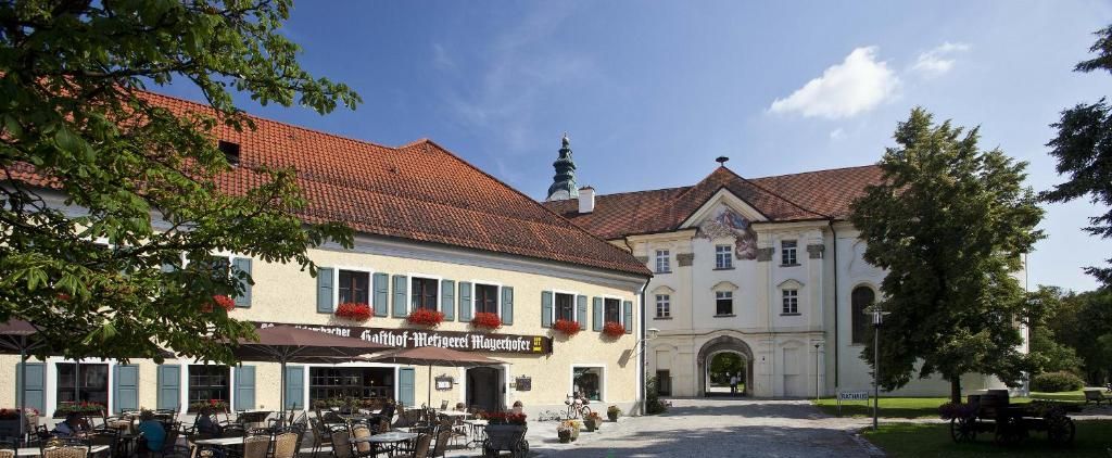 A building with outdoor seating and a sign for 'Mayerhofer Hotel - Restaurant - Metzgerei - Tagung'.
