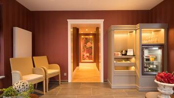 A hotel lobby with a reception desk, seating area, and a refrigerator stocked with beverages.