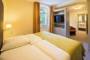 Ein Hotelzimmer mit Bett, Fernseher, Schreibtisch und Bad.