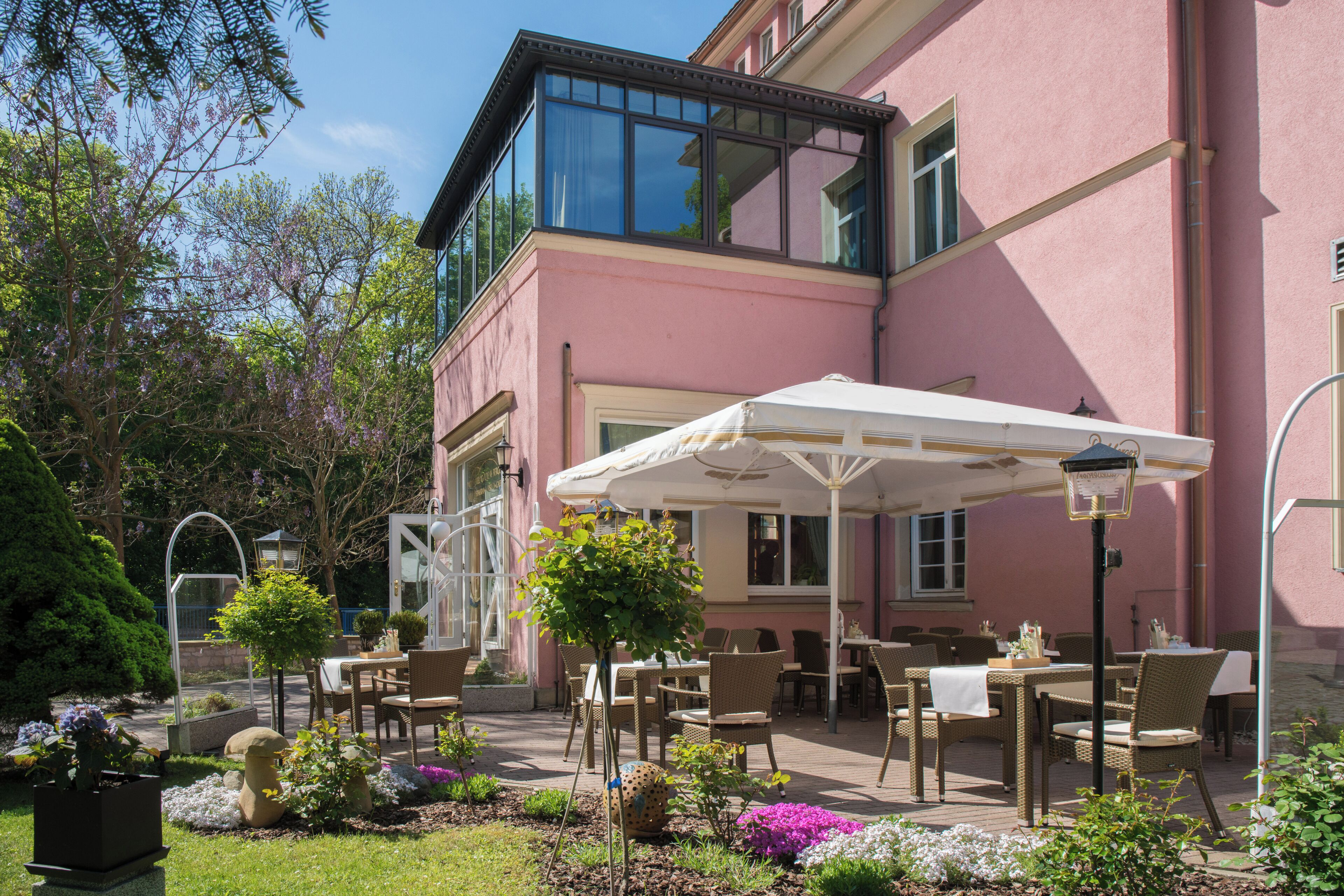 A building with a pink exterior, outdoor seating area with wicker furniture, and a covered patio.