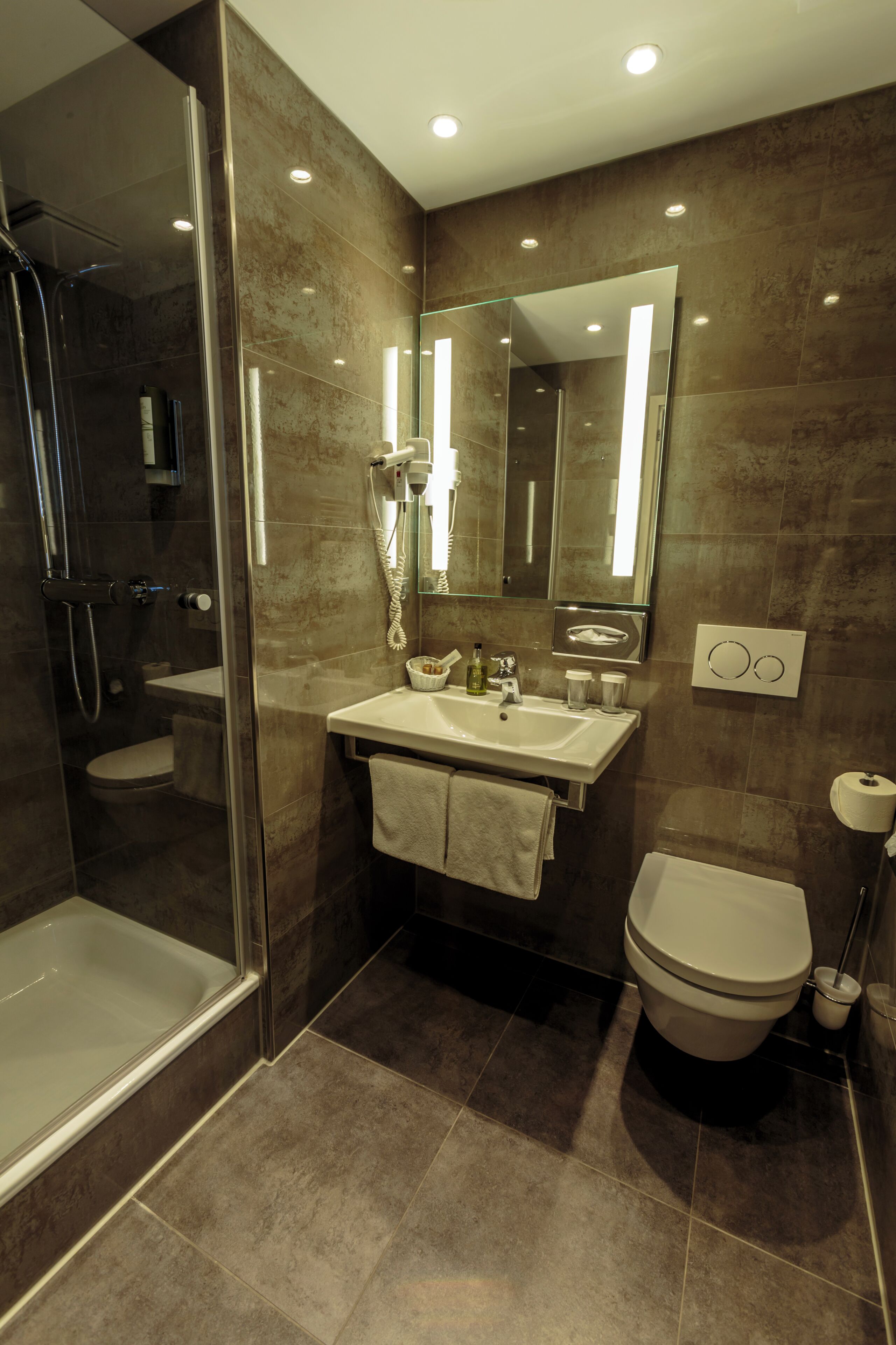 Ein modernes Badezimmer mit einer gläsernen Duschkabine, einem Waschtisch mit Spiegel und einer Toilette.