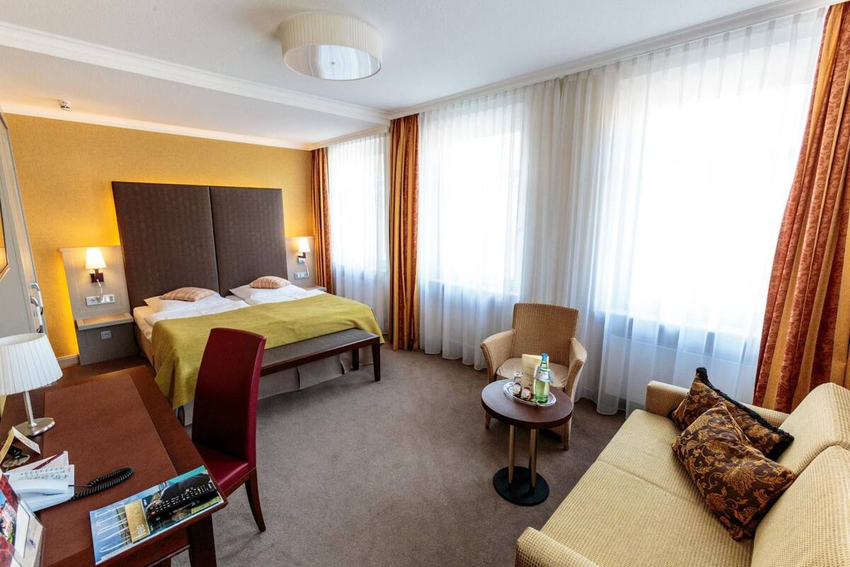 Habitación de hotel con cama, escritorio, silla, sofá y una mesita con bandeja.