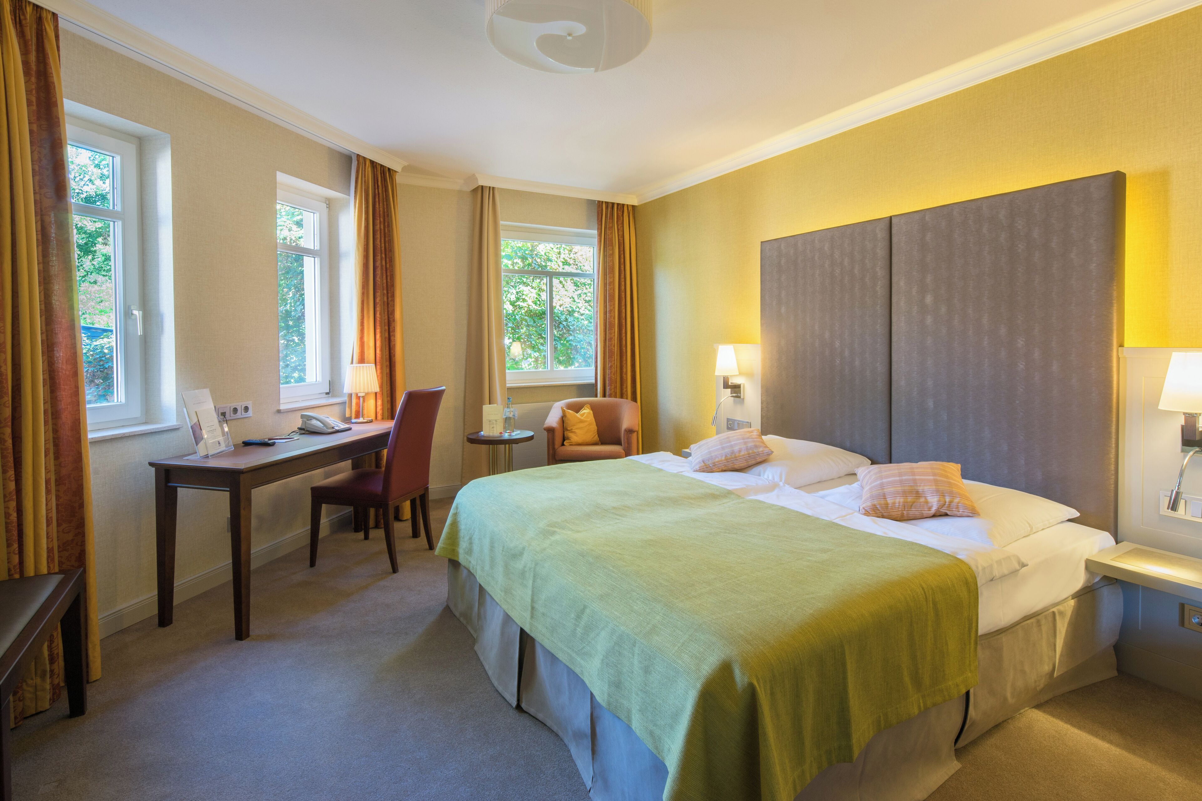 Ein Hotelzimmer mit einem Bett, einem Schreibtisch, einem Sessel und einem Fenster.