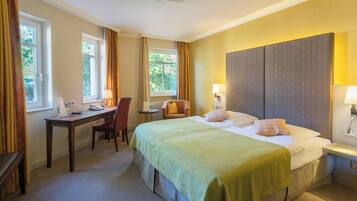 Ein Hotelzimmer mit einem Bett, einem Schreibtisch, einem Sessel und einem Fenster.