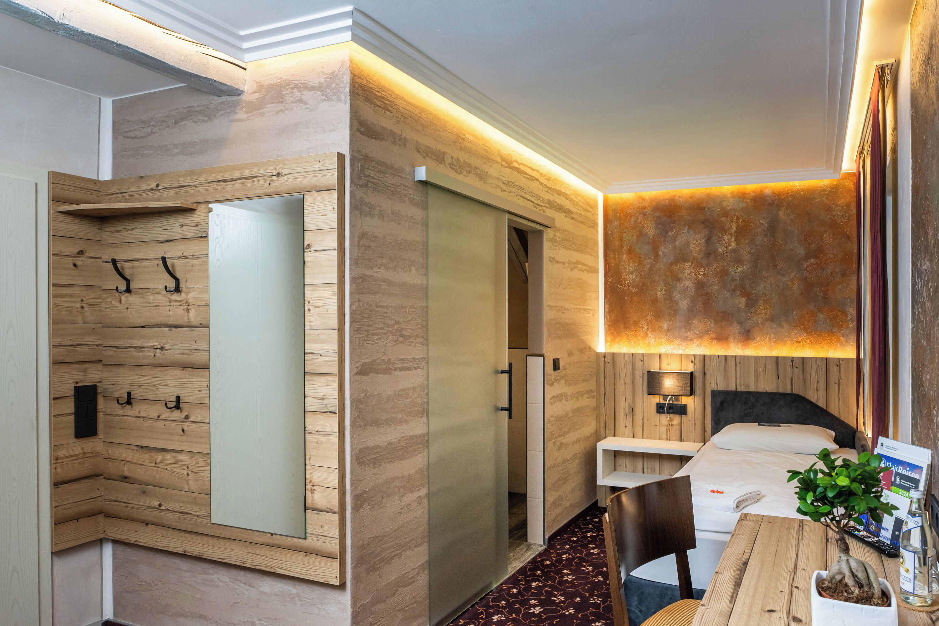 Una habitación de hotel con pared de madera, una cama, un escritorio y una silla.
