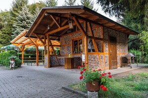 Un edificio rústico de madera con fachada de ladrillo, un patio cubierto y un pequeño espacio al aire libre para sentarse.