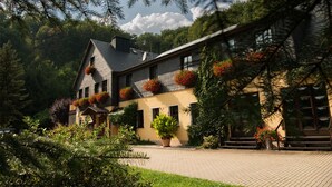 A two-story building with a sloped roof, large windows, and a brick pathway leading to the entrance. - Flair Hotel Mellestollen (Saalfeld-Saale)