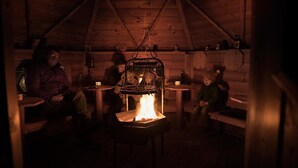 A cozy cabin interior with a central fireplace, wooden walls, and a sloped ceiling. - Flair Hotel Mellestollen (Saalfeld-Saale)