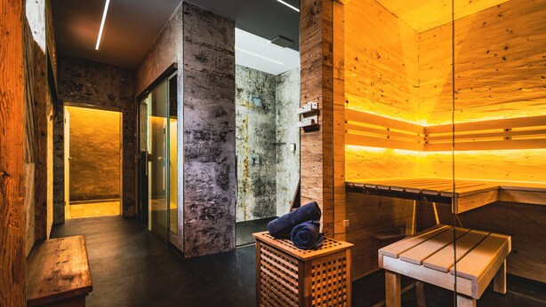 A sauna room with wooden walls and benches, a wooden bench with towels, and a bench with a towel. - Flair Hotel Mellestollen (Saalfeld-Saale)
