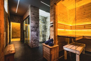 Una sala de sauna con paredes y bancos de madera, un banco con toallas y otro banco con una toalla.