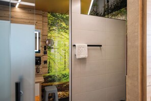 A bathroom with a wooden wall, a towel hanging on a rack, and a wall-mounted phone. - Flair Hotel Mellestollen (Saalfeld-Saale)