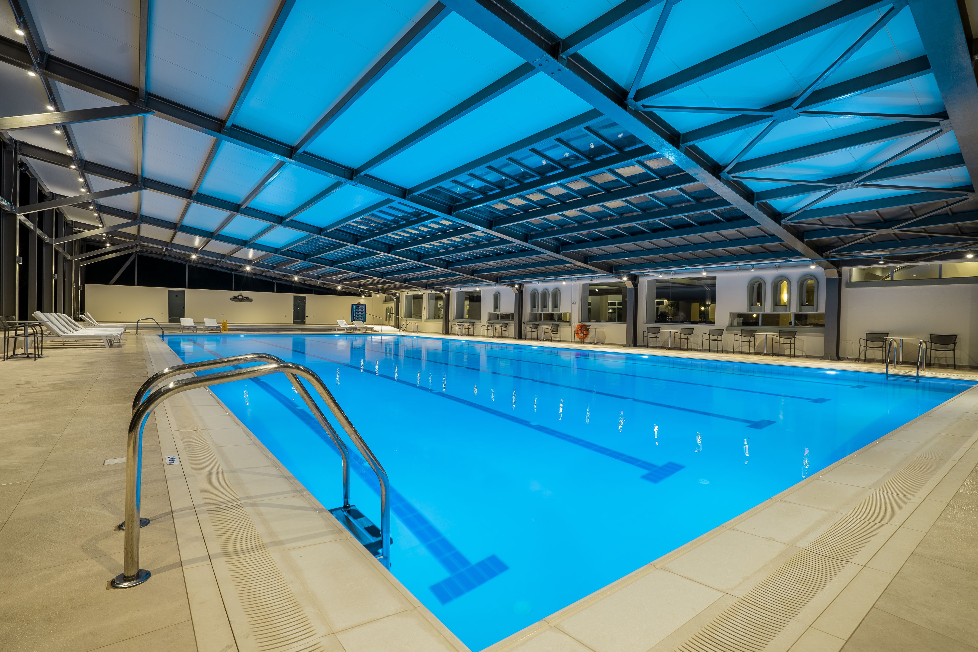 Ein Hallenbad mit blau schimmernder Decke und einer Metallleiter.