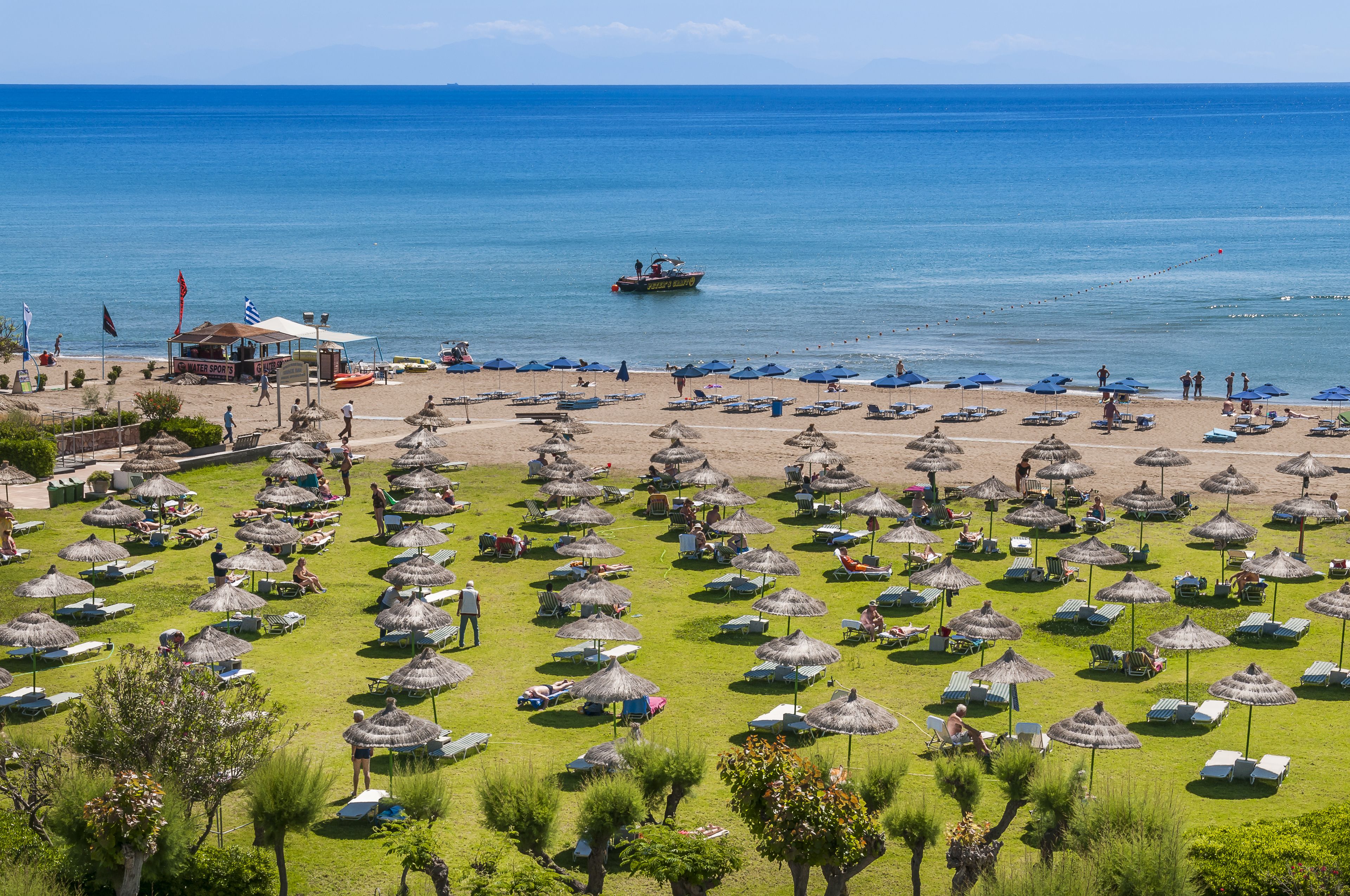 Praia particular, guarda-sóis, prática de vôlei de praia 