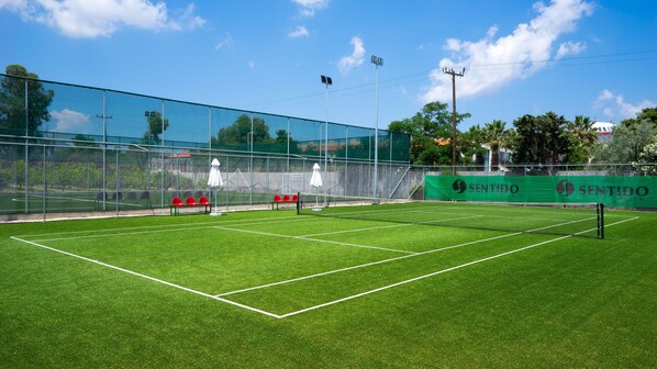 A tennis court with a net, seating area, and a banner.