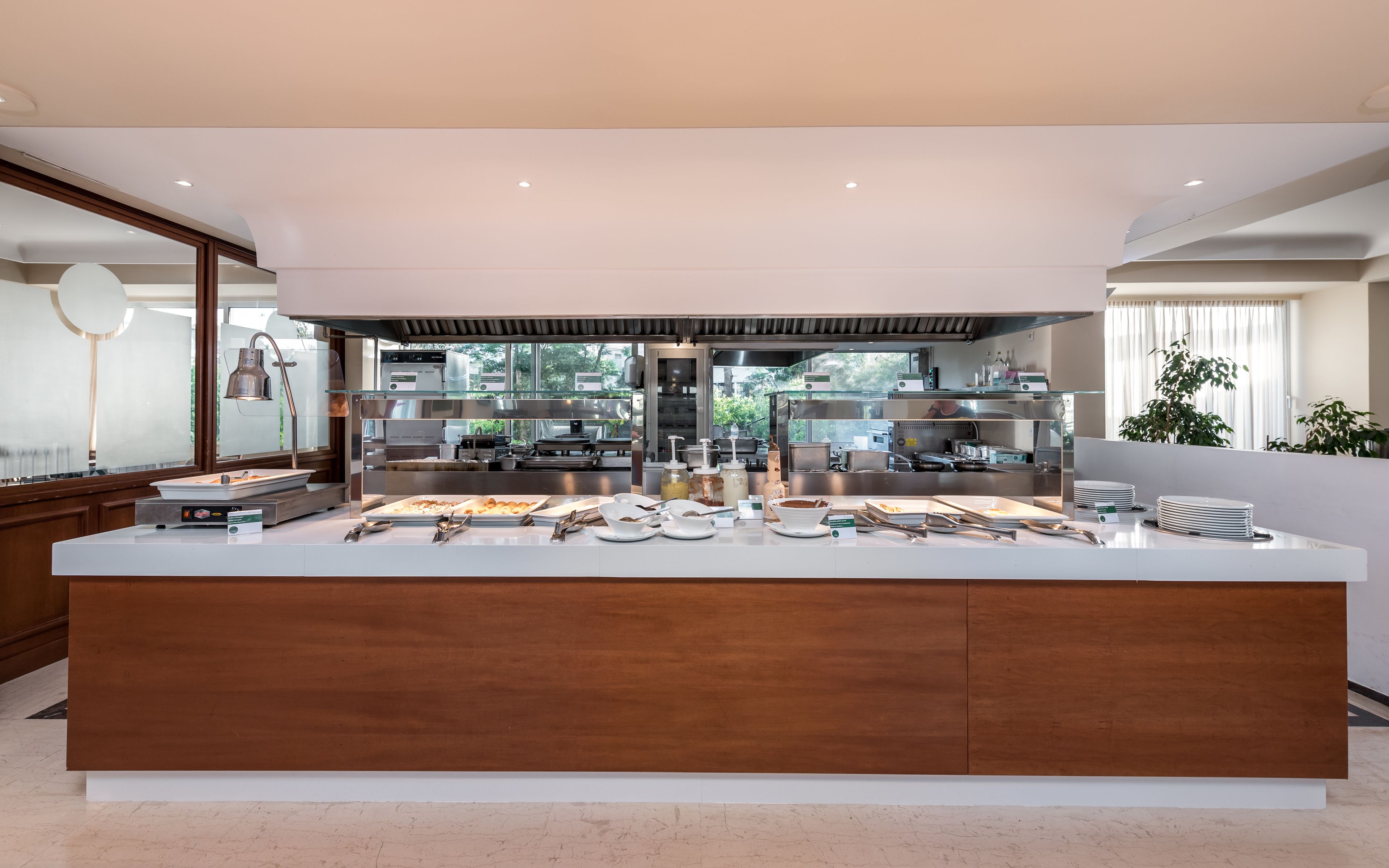 A modern kitchen with a central island, stainless steel appliances, and a view of the outdoors.