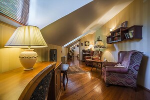A cozy living room with a wooden coffee table, a patterned armchair, and a bookshelf.