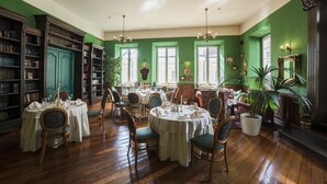 A dining area with round tables, chairs, and bookshelves. - Shakespeare Boutique Hotel (Vilnius)