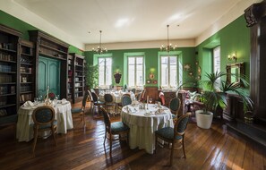 A dining area with round tables, chairs, and bookshelves. - Shakespeare Boutique Hotel (Vilnius)