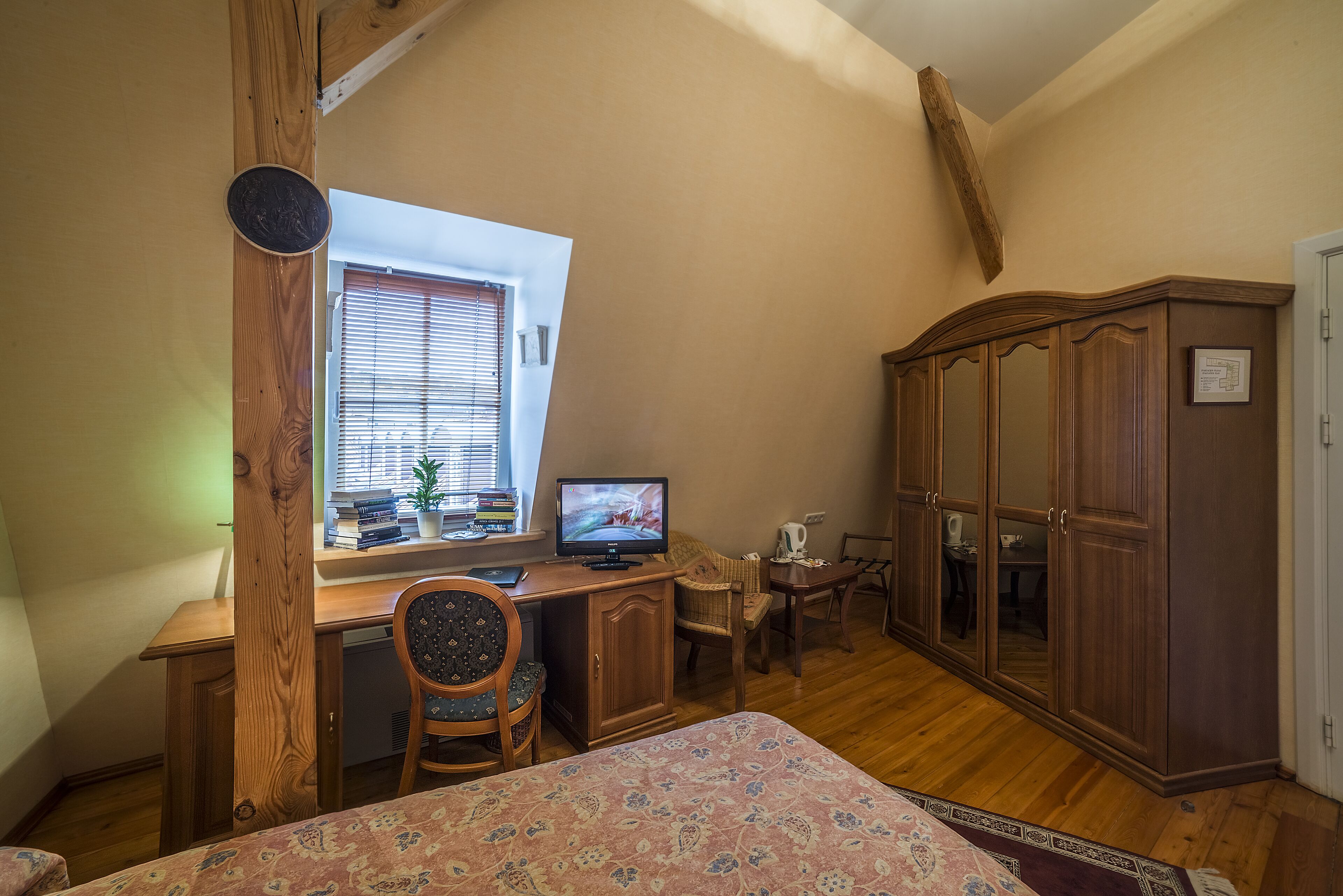 Un dormitorio con un escritorio de madera, televisión, armario y cama.