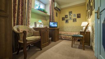 Una habitación acogedora con televisión, dos sillones, una mesita y un ventanal con cortinas.