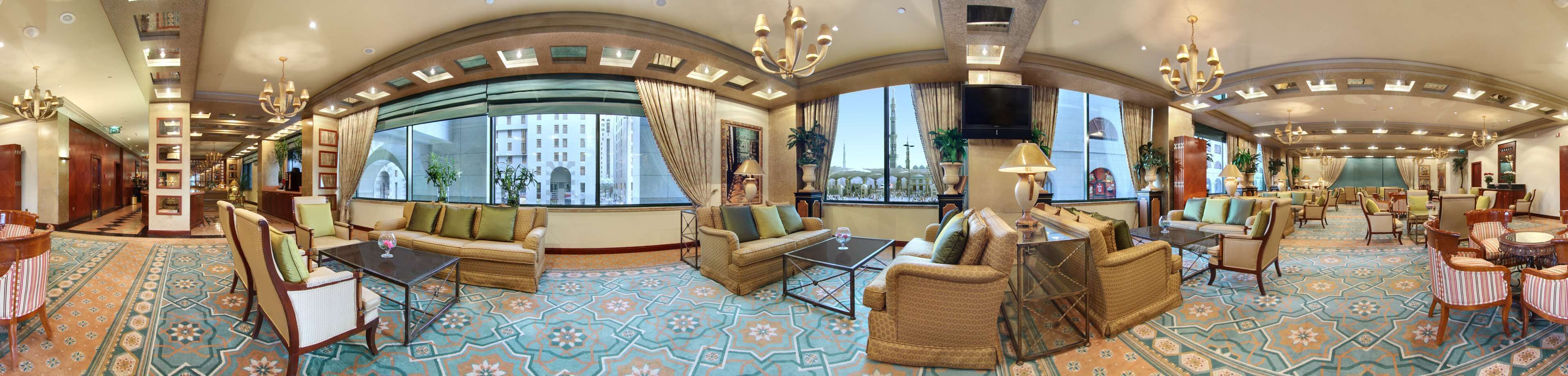A luxurious hotel lobby with a large seating area, a bar, and a view of a cityscape.