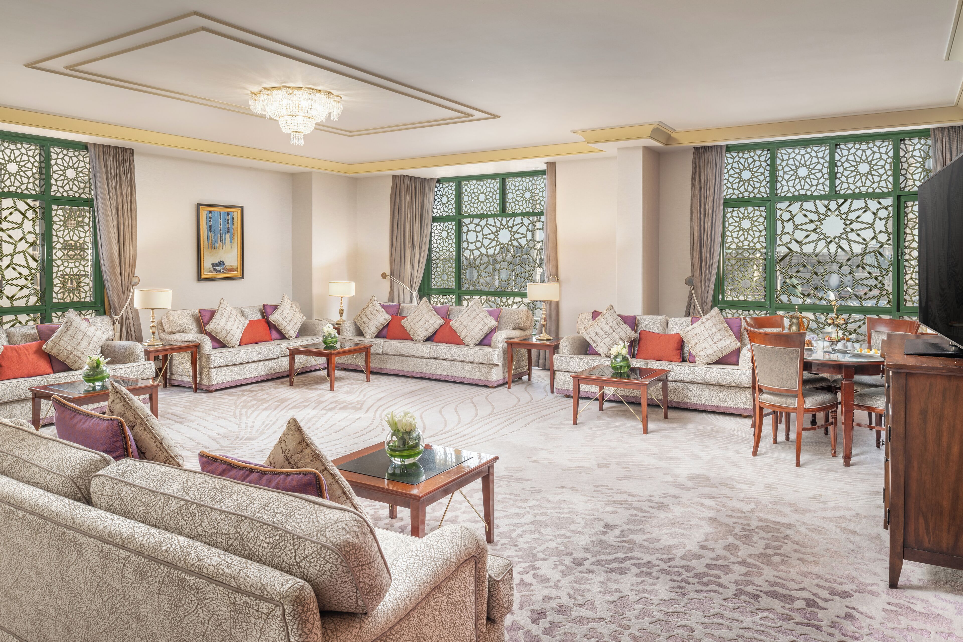 A spacious living room with a sofa set, a dining table, and a chandelier.