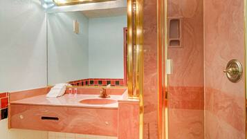 Een badkamer met een wastafel, spiegel en douche.