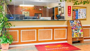 Una zona d'entrada amb mostrador, cartell de benvinguda, directori i catifa vermella amb el logotip d'Econolodge.