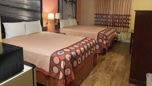 A hotel room with two beds, a desk, a television, and a painting of a beach scene. - Harvest Inn, Dixon/ UC Davis. (Dixon)